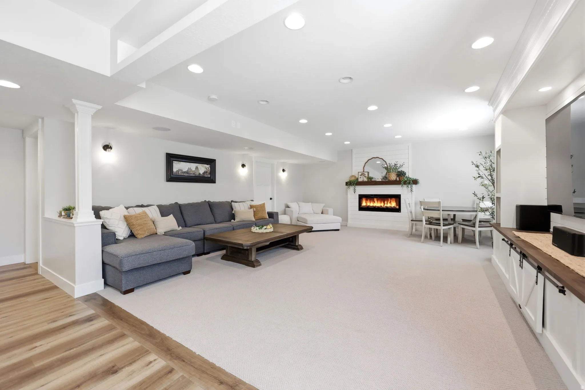 Spacious open-concept room featuring recessed lighting, a modern fireplace with a white brick surround, and a wood mantel