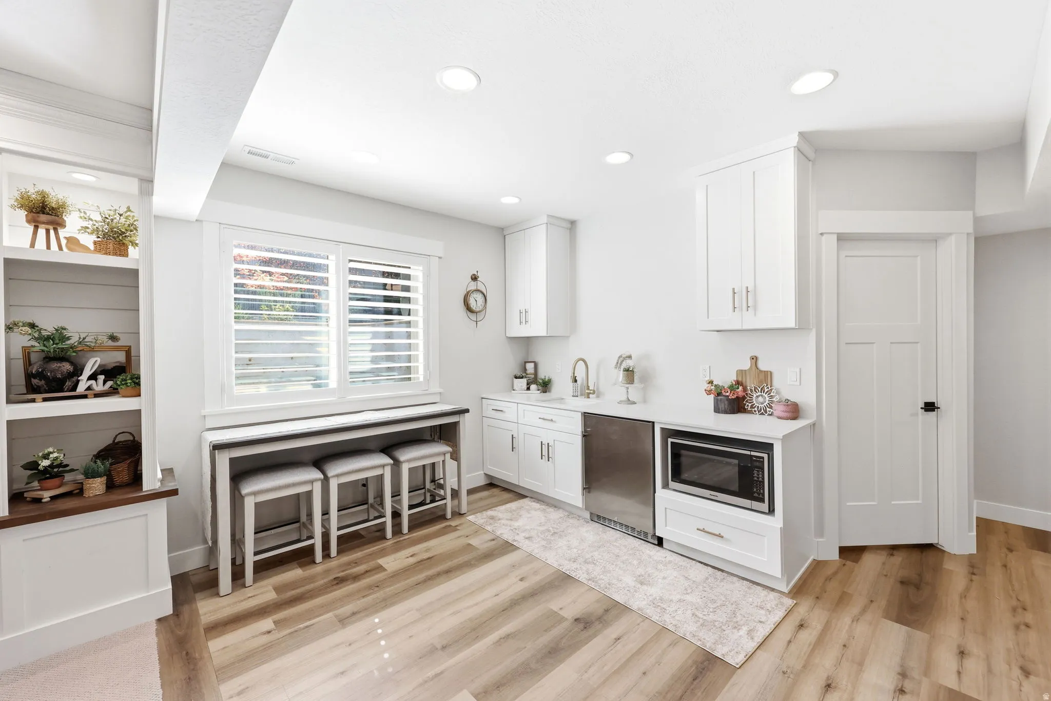 Kitchenette featuring white cabinetry, a built-in microwave, a stainless steel under-counter refrigerator, and a stainless steel sink with a gooseneck faucet