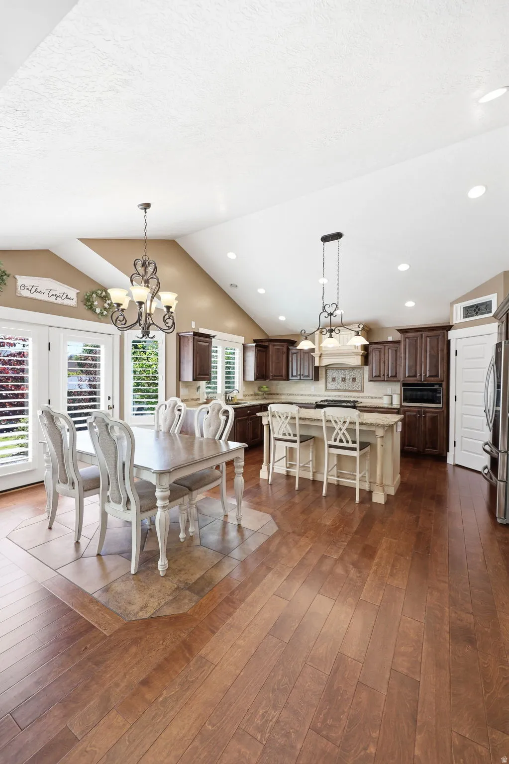 Kitchen and dining area featuring wood-finish flooring, vaulted ceilings, and recessed lighting