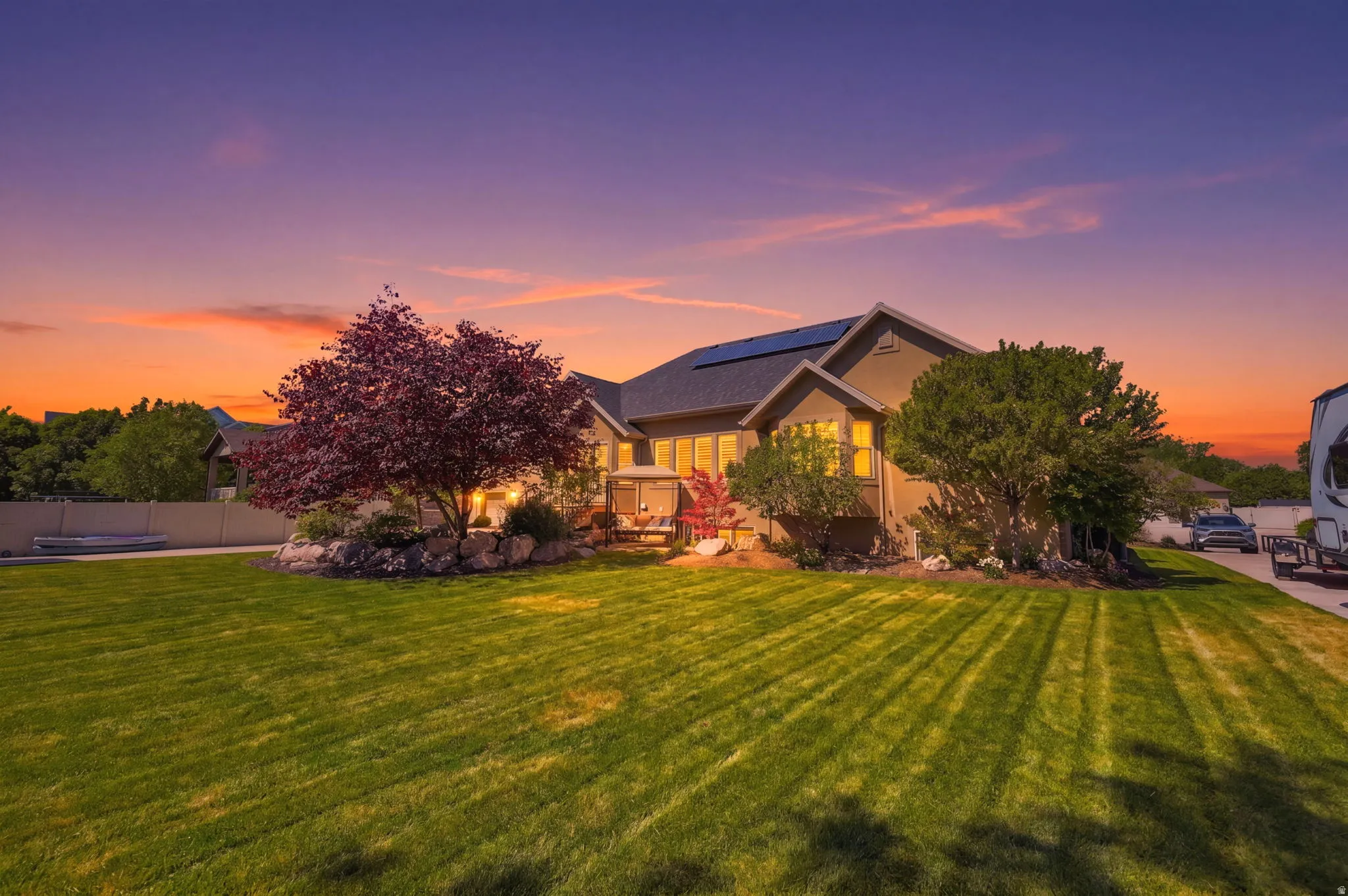 Spacious exterior featuring a large, manicured lawn, established landscaping with mature trees, and a multi-level home with solar panels