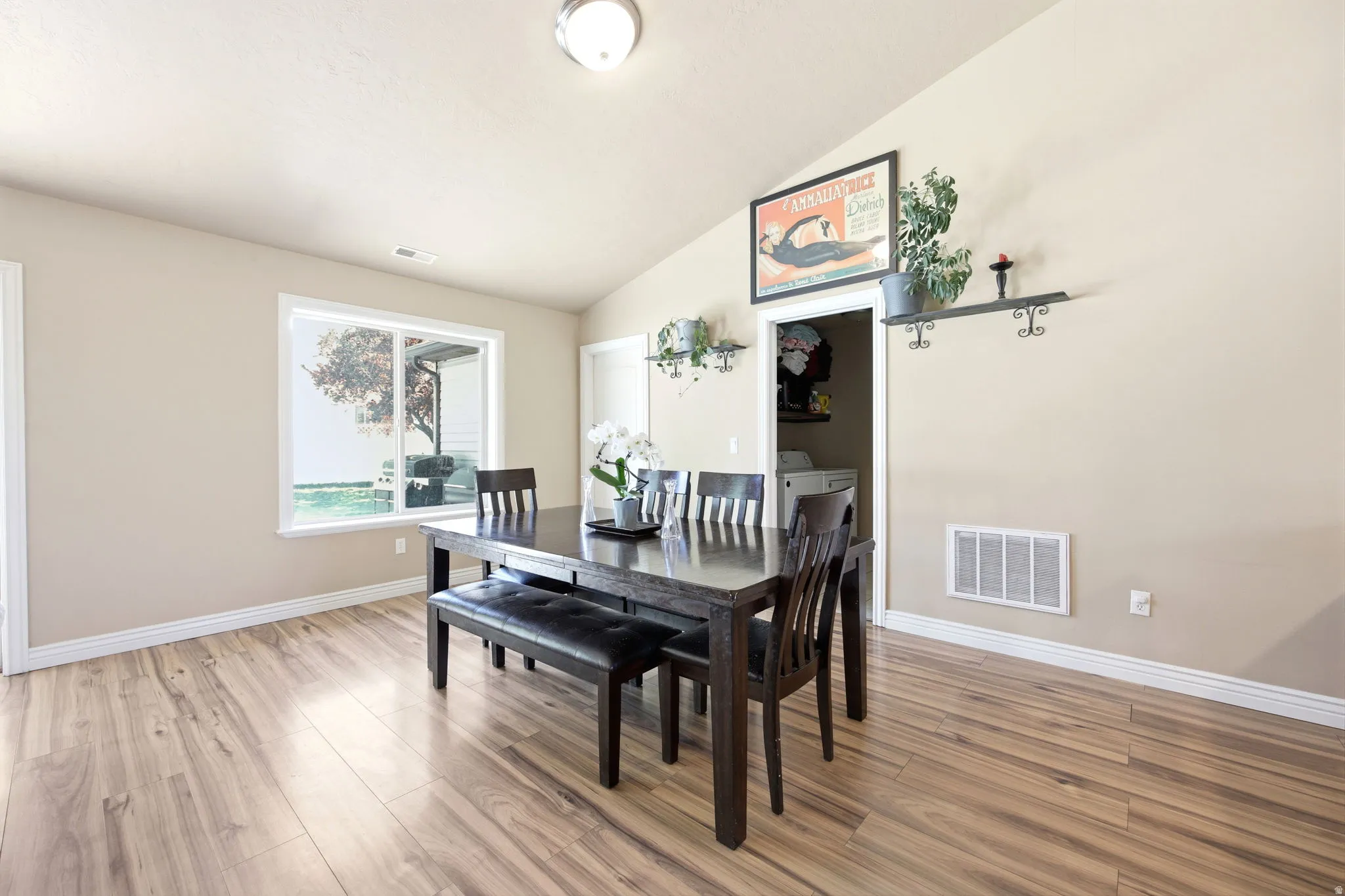 Open-concept room featuring wood-finish flooring, a vaulted ceiling, and a large window