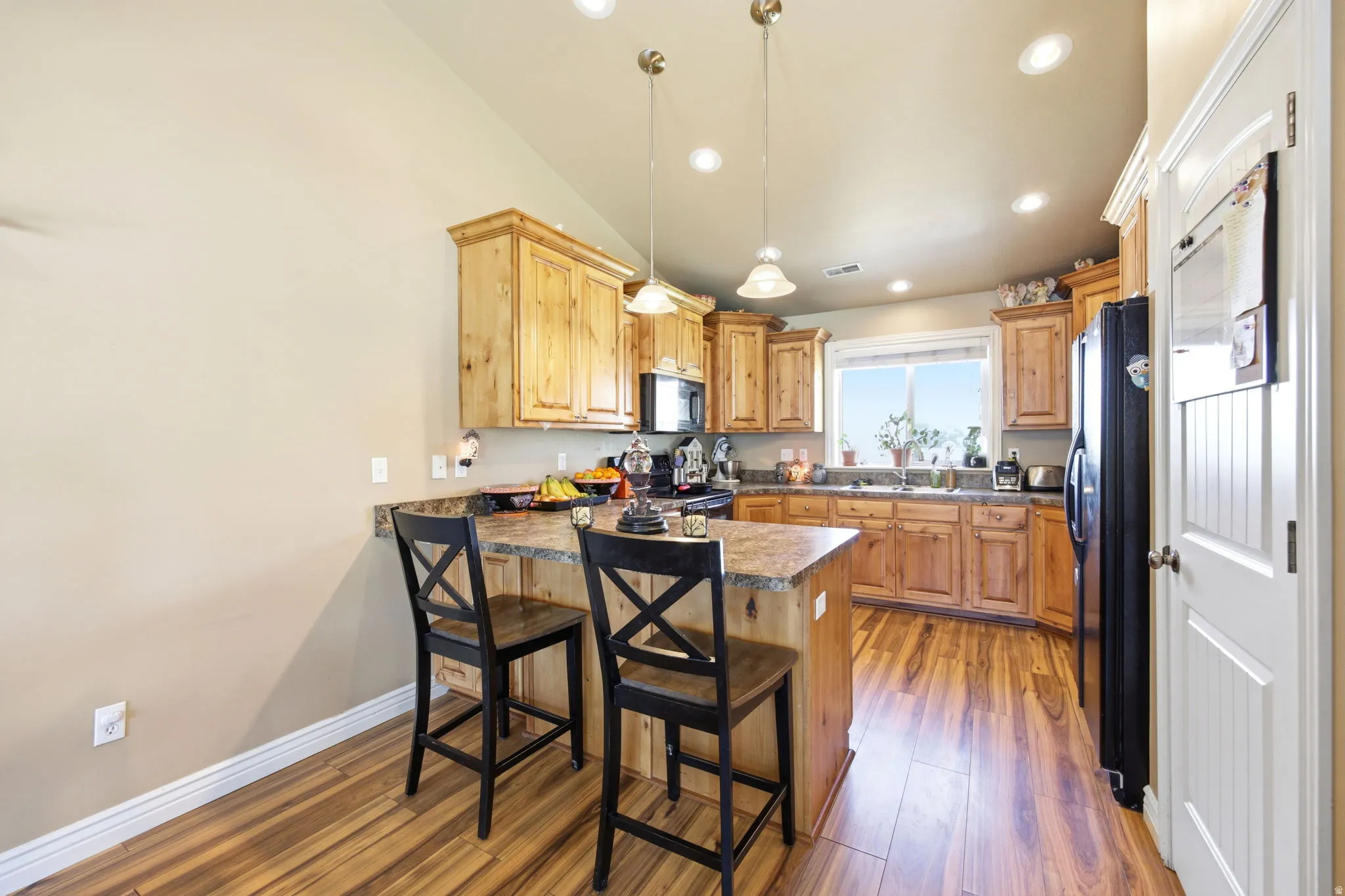 Kitchen featuring wood-finish flooring, recessed lighting, wood cabinetry, and a peninsula with a stone-finish countertop
