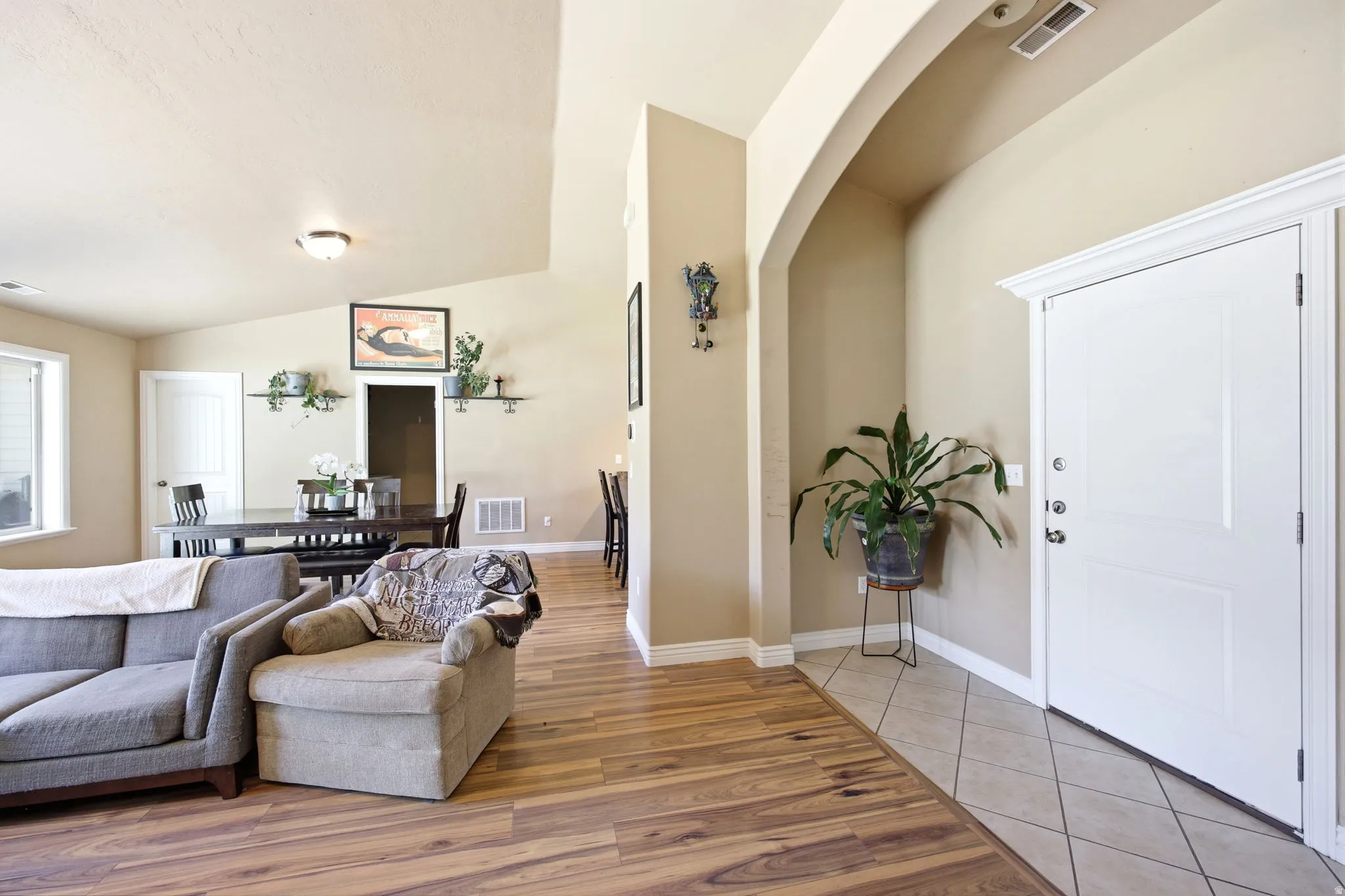 Entryway featuring a white paneled door with polished hardware, tile flooring, and an arched architectural detail