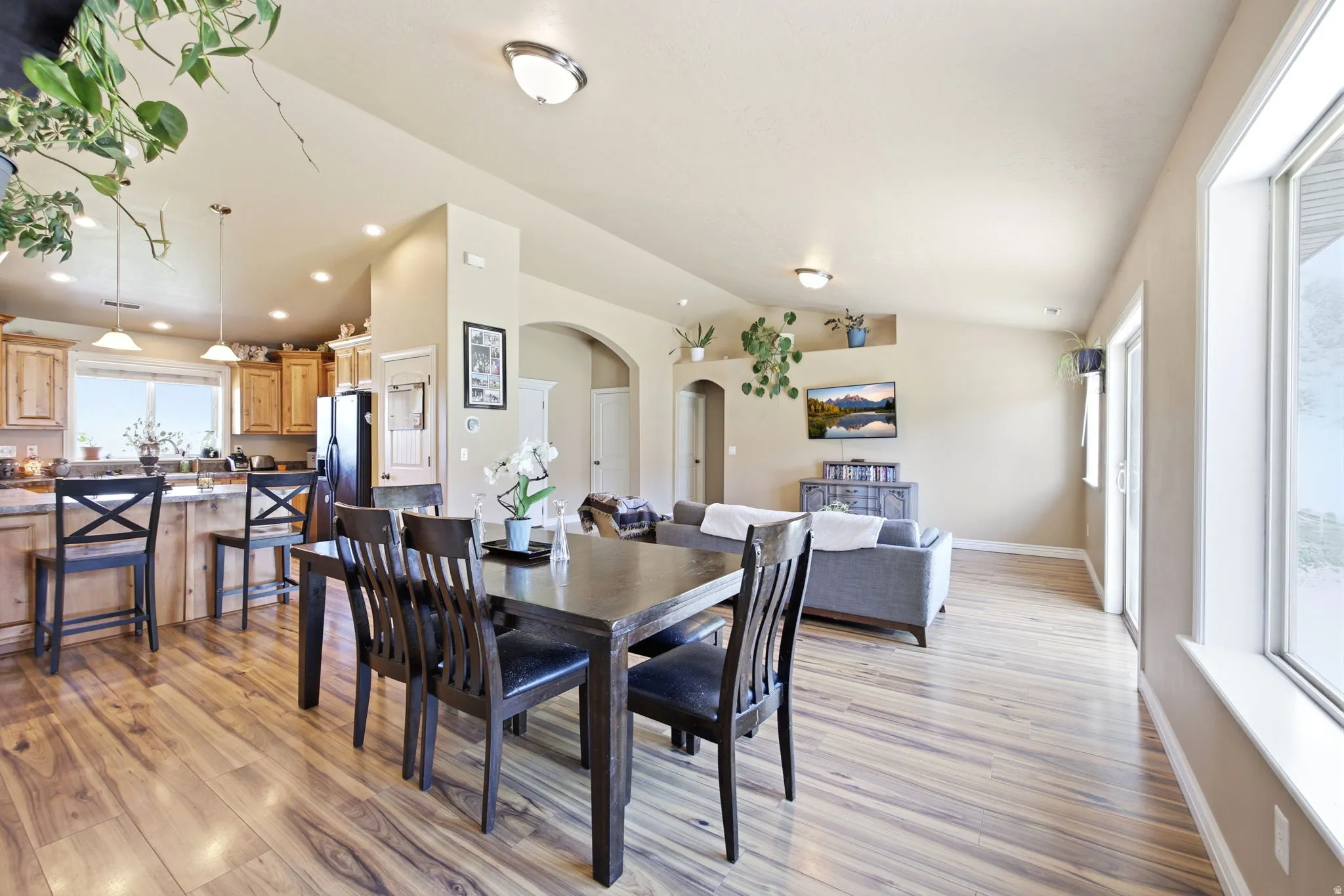 Open-concept living area featuring wood-finish flooring, vaulted ceilings, and recessed lighting