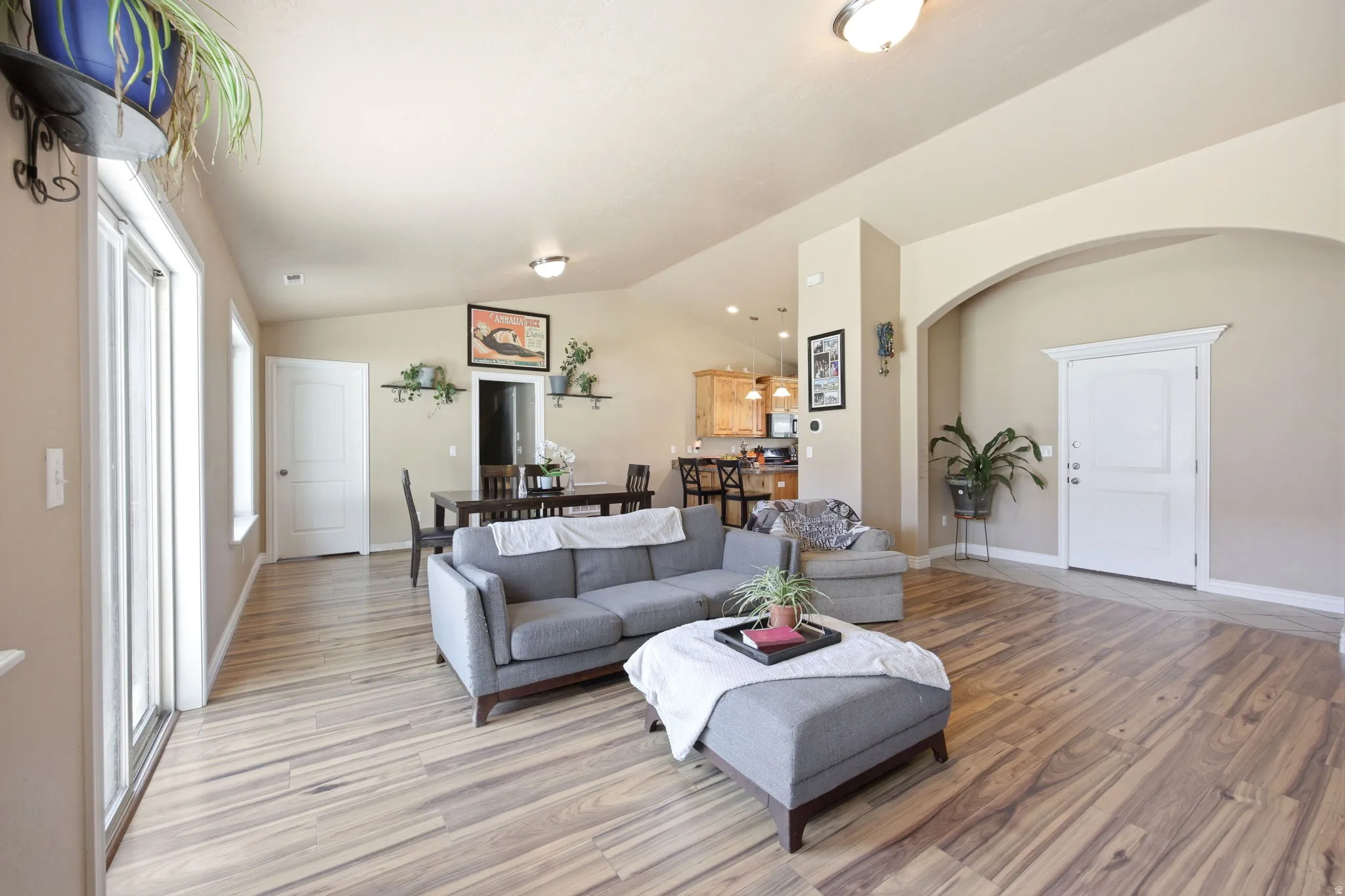 Spacious living area featuring wood-finish flooring, vaulted ceilings, and an arched entry