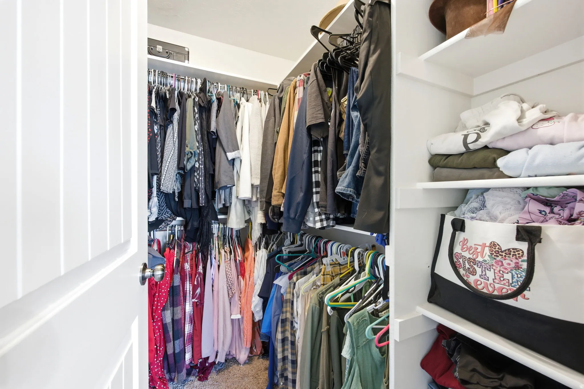 Walk-in closet with white shelving, multiple hanging rods, and an overhead storage shelf