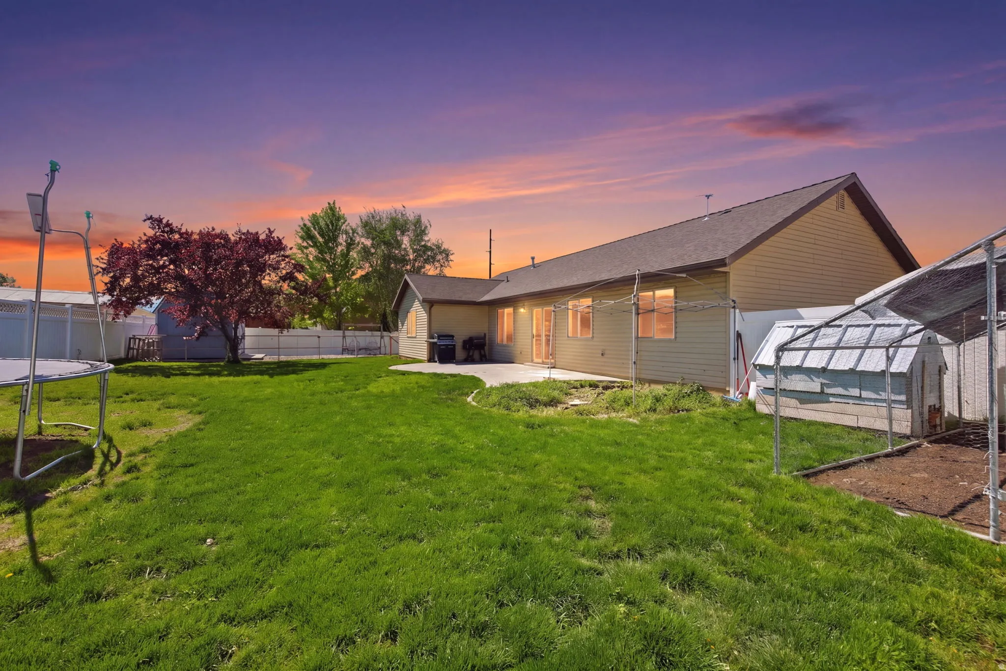 Expansive backyard featuring a lush lawn and a mature red-leaf tree