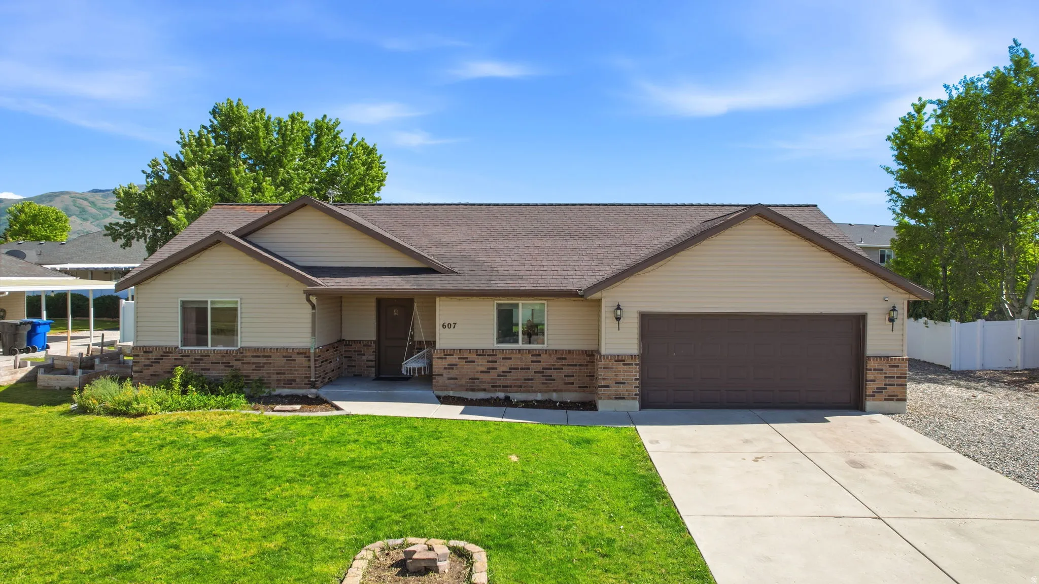 Ranch-style residence featuring a two-car garage, partial brick facade, light-colored siding, and a gabled roofline