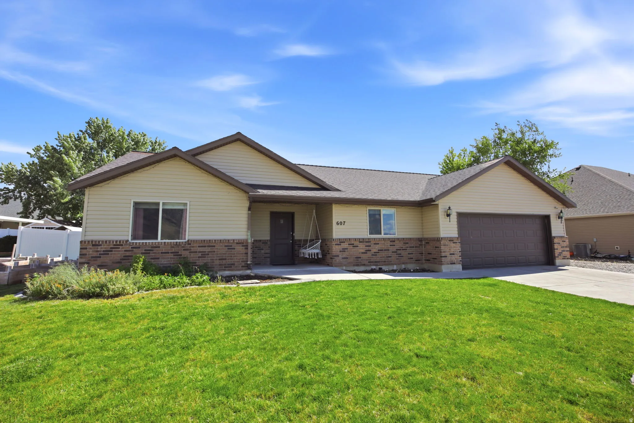 Ranch-style residence featuring a brick and siding exterior, an attached two-car garage, a concrete driveway, and a front lawn