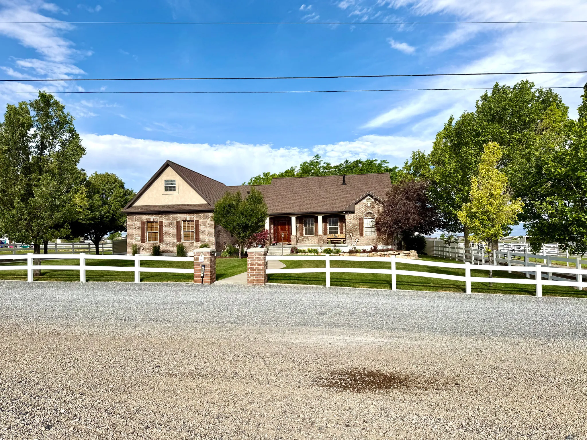 Expansive residence featuring a brick and siding exterior, a gabled roofline, and a covered front porch with columns