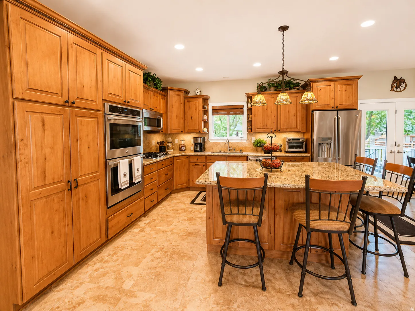 Spacious kitchen featuring extensive wood cabinetry, stainless steel double ovens, and a large center island with a stone countertop