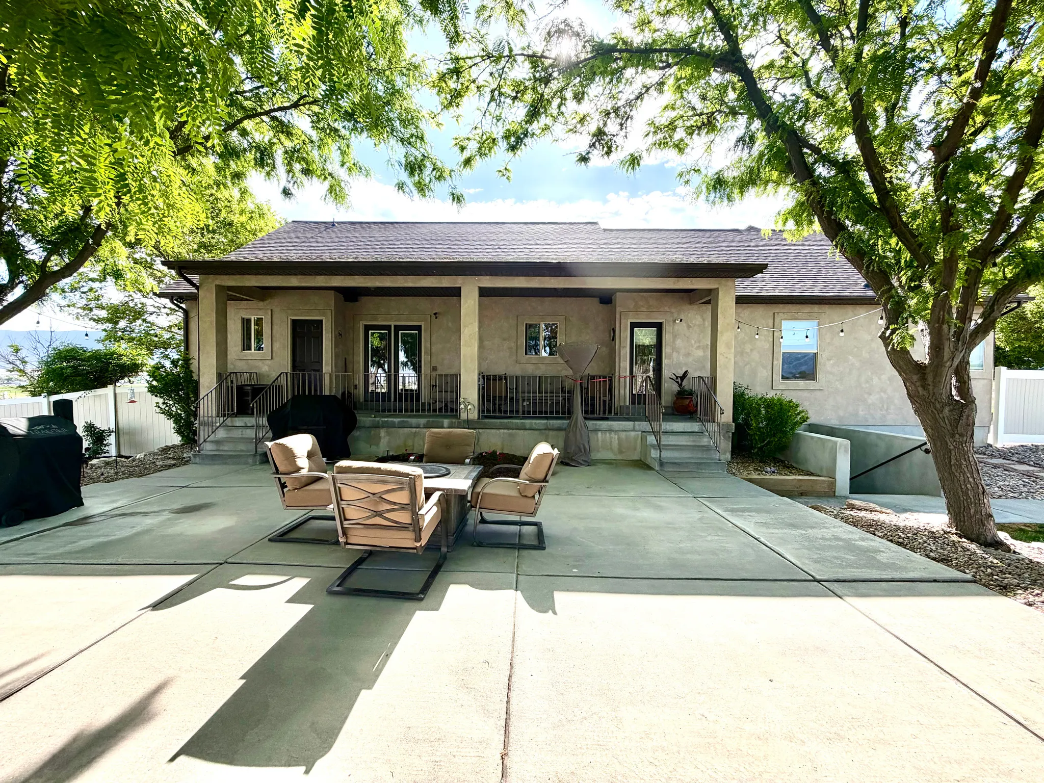 Expansive concrete patio area with a covered porch featuring stucco siding