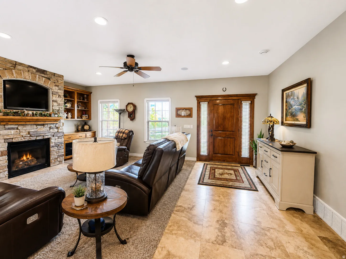 Spacious living area featuring a stone-clad fireplace with a built-in television alcove and wood mantel
