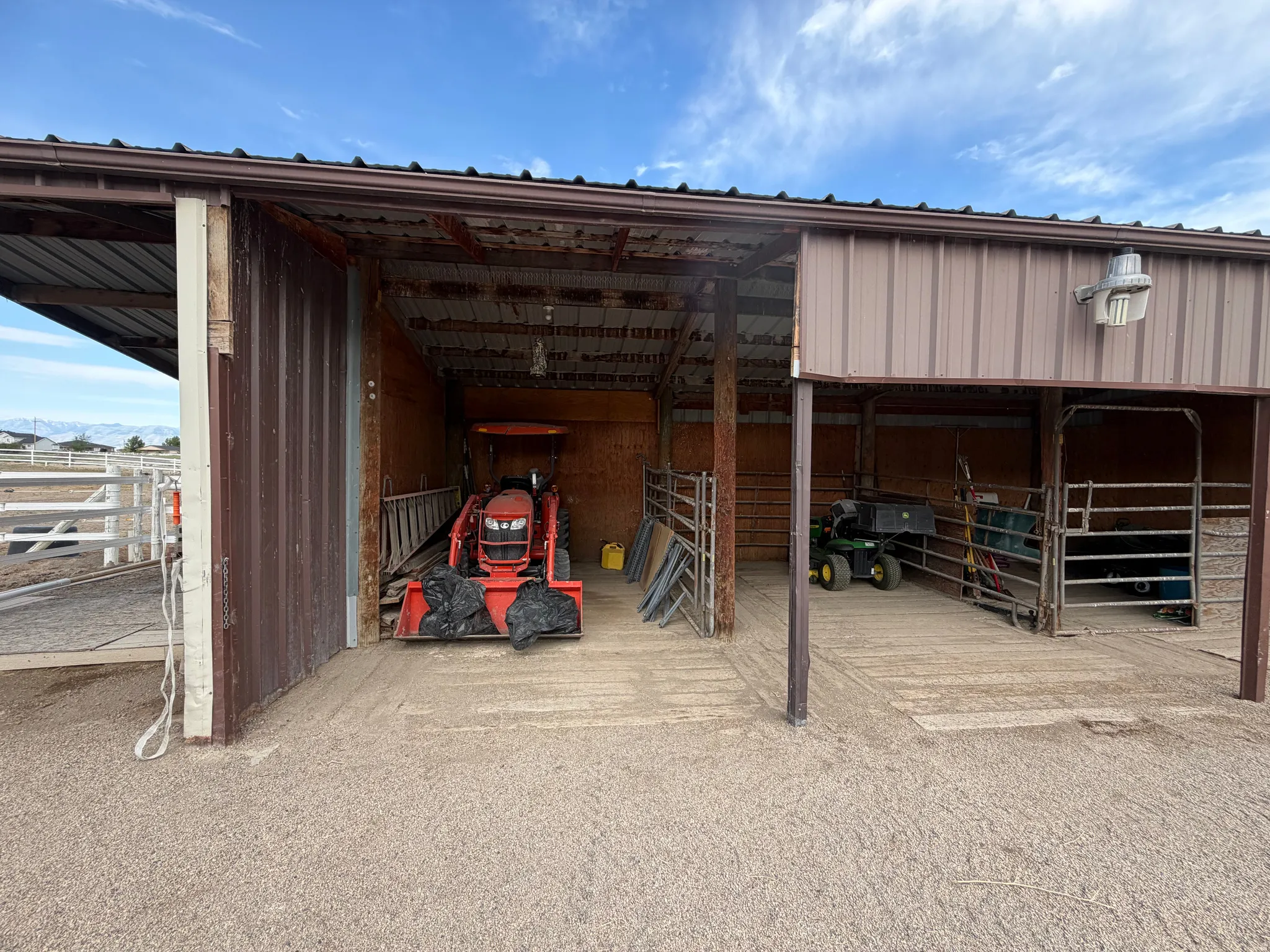Metal-sided barn structure with multiple open bays and a gravel floor
