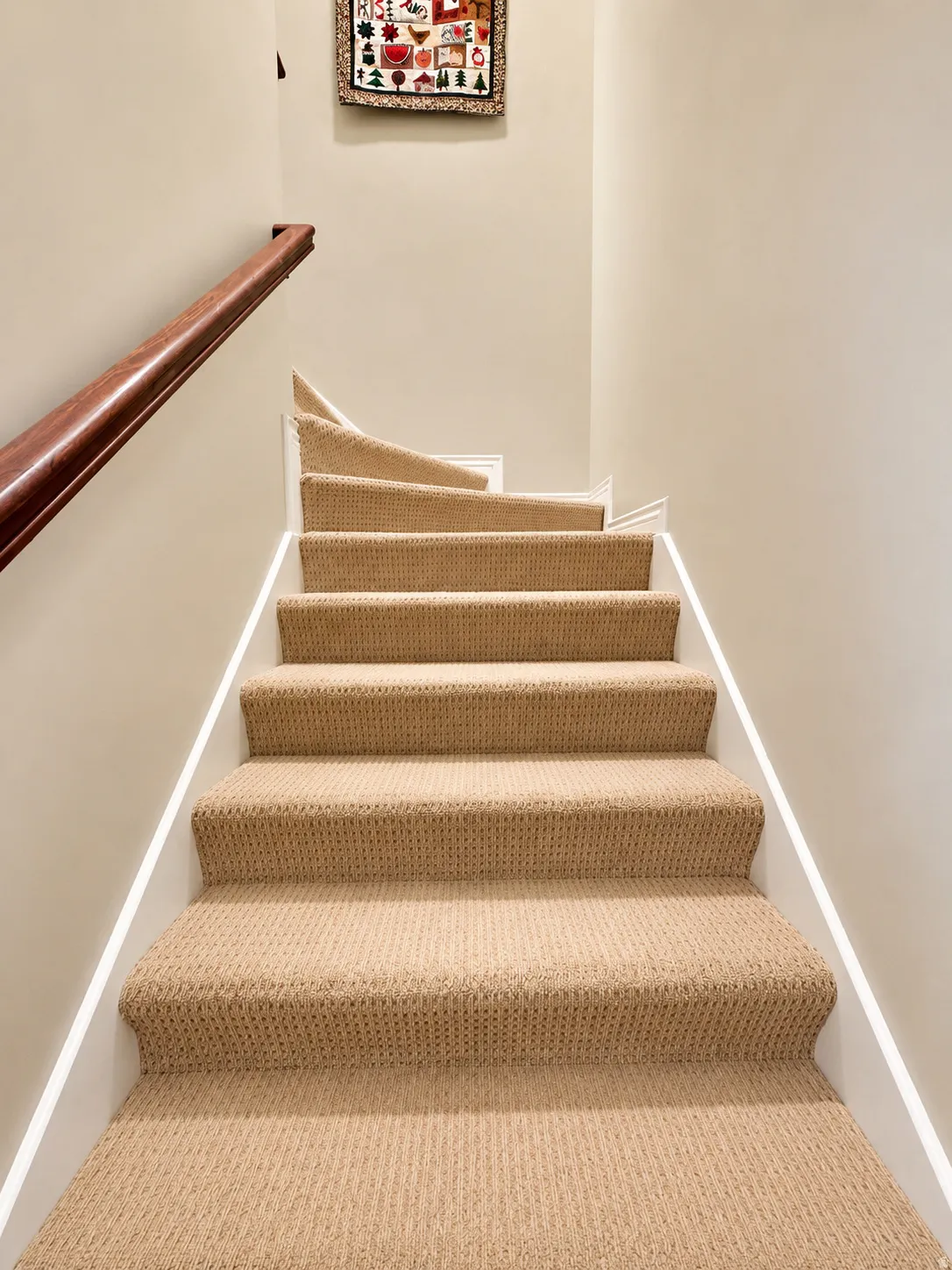 Staircase featuring neutral carpeting, a polished wood handrail, and white trim