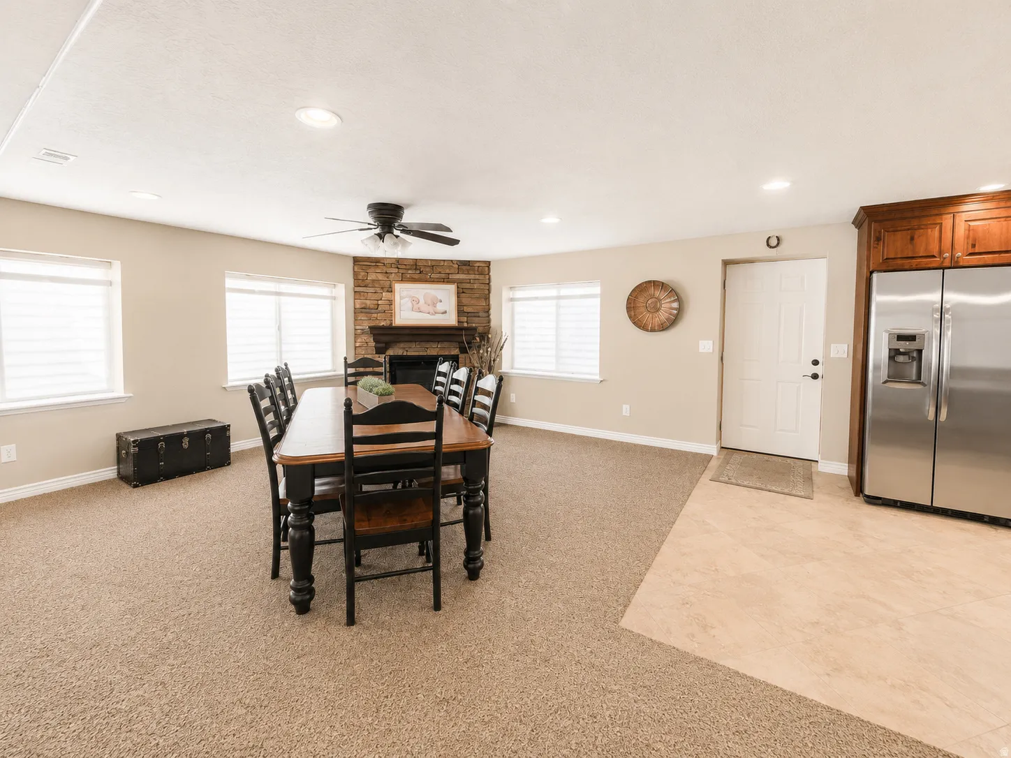 Open-concept living space featuring a stacked stone fireplace with a wood mantel, recessed lighting, and a ceiling fan