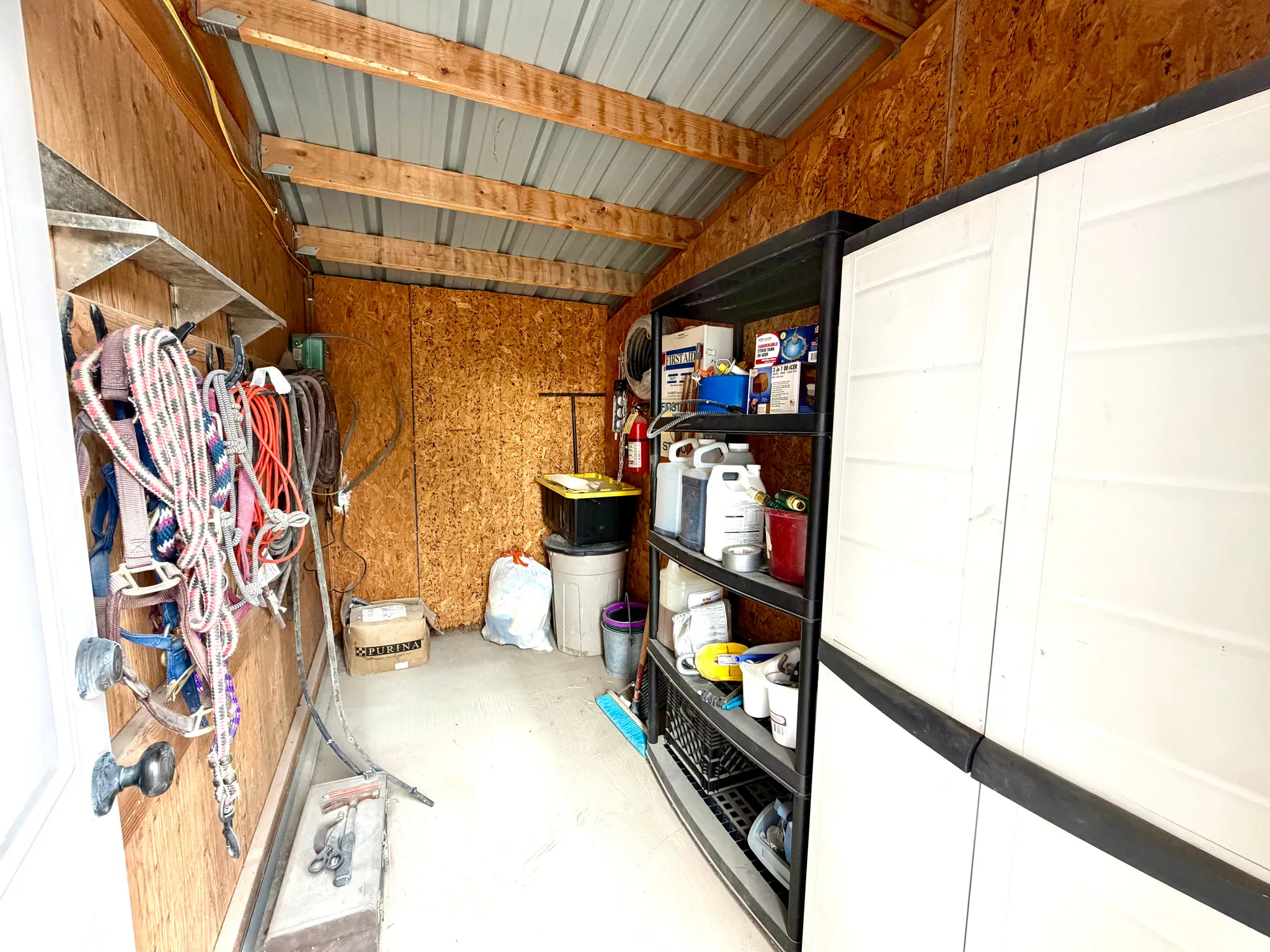 Enclosed storage structure featuring exposed wood paneling, metal ceiling, and concrete flooring