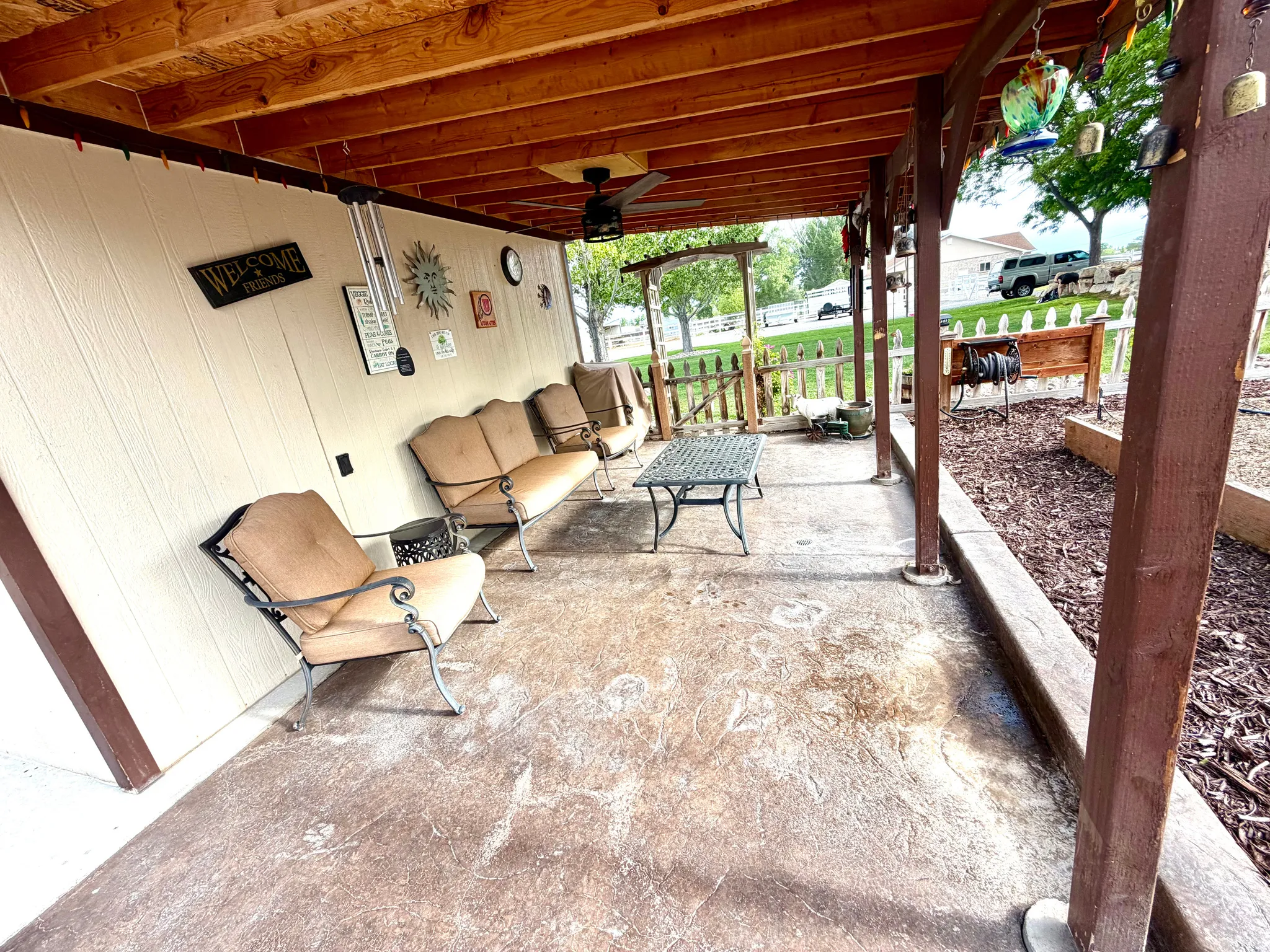 Covered patio featuring an exposed wood beam ceiling, stained concrete flooring, and an exterior wall with vertical siding