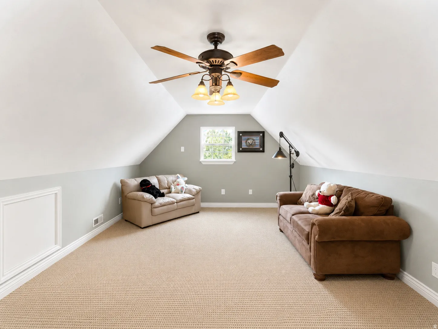 Carpeted room featuring a ceiling fan with light fixture, a window, and sloped ceilings