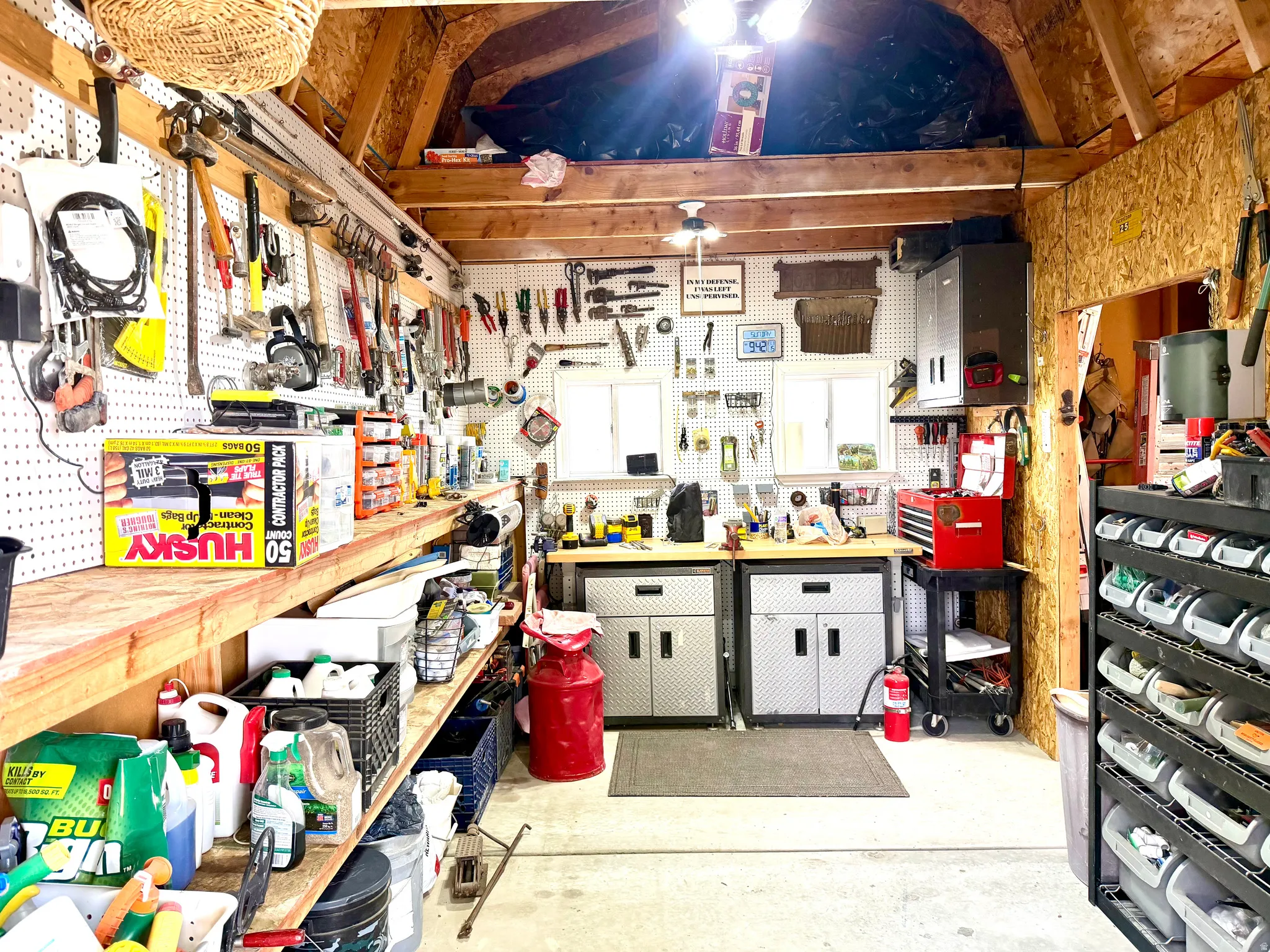 Spacious utility shed featuring exposed wood framing, concrete flooring, and ample pegboard storage
