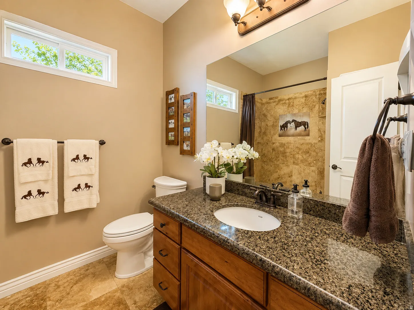 Bathroom featuring a wood-finish vanity with a granite-style countertop and an undermount sink