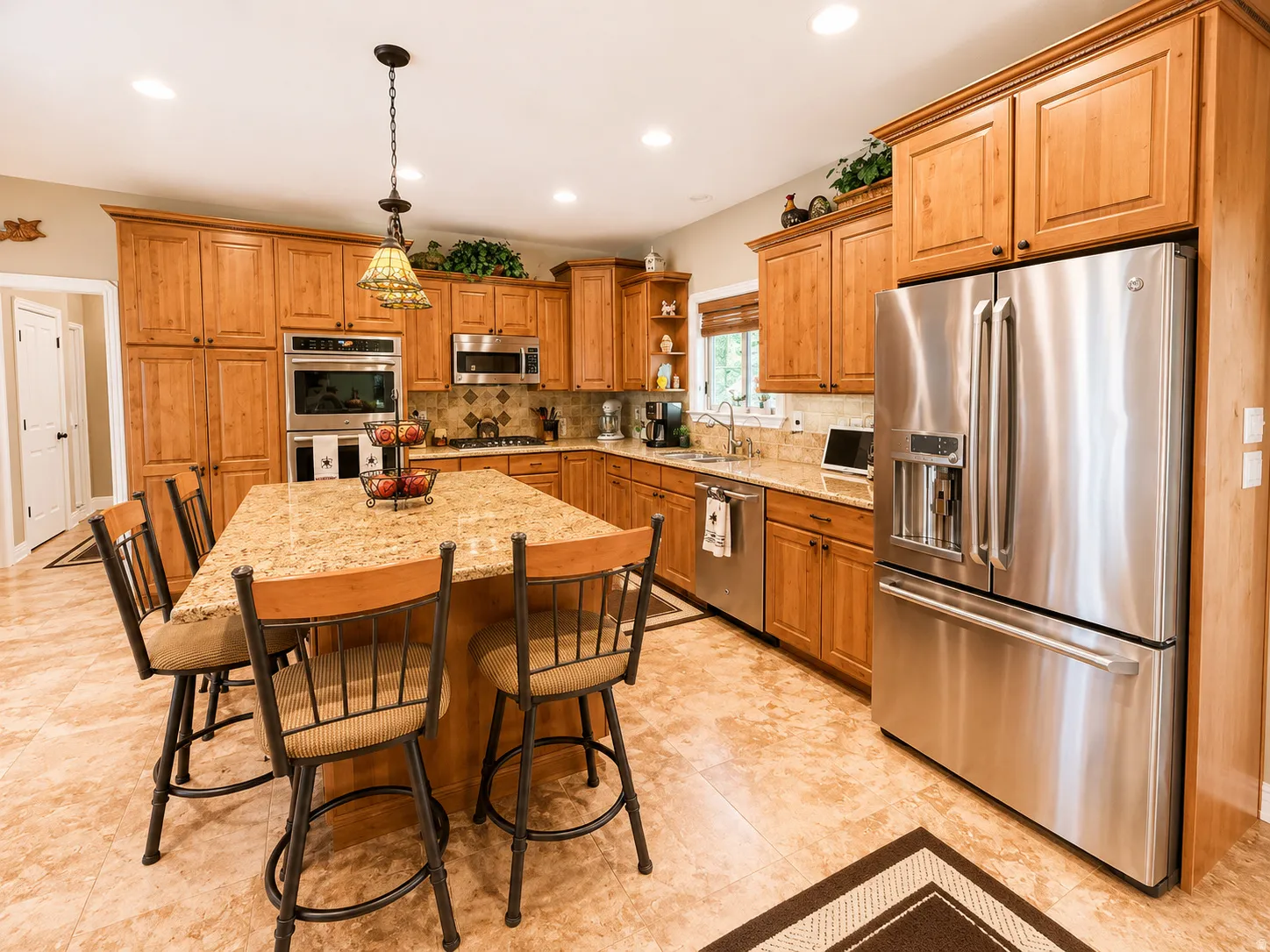 Kitchen featuring a central island with granite countertop, extensive wood cabinetry, stainless steel appliances, recessed lighting, and patterned tile flooring