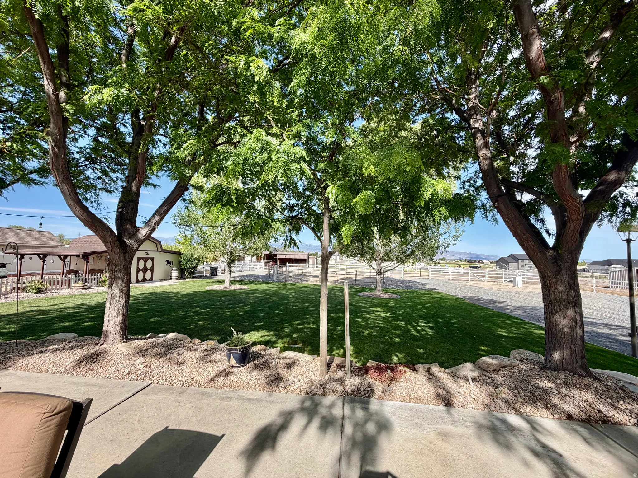 Spacious outdoor area with a concrete patio, mature trees, and a gravel bed