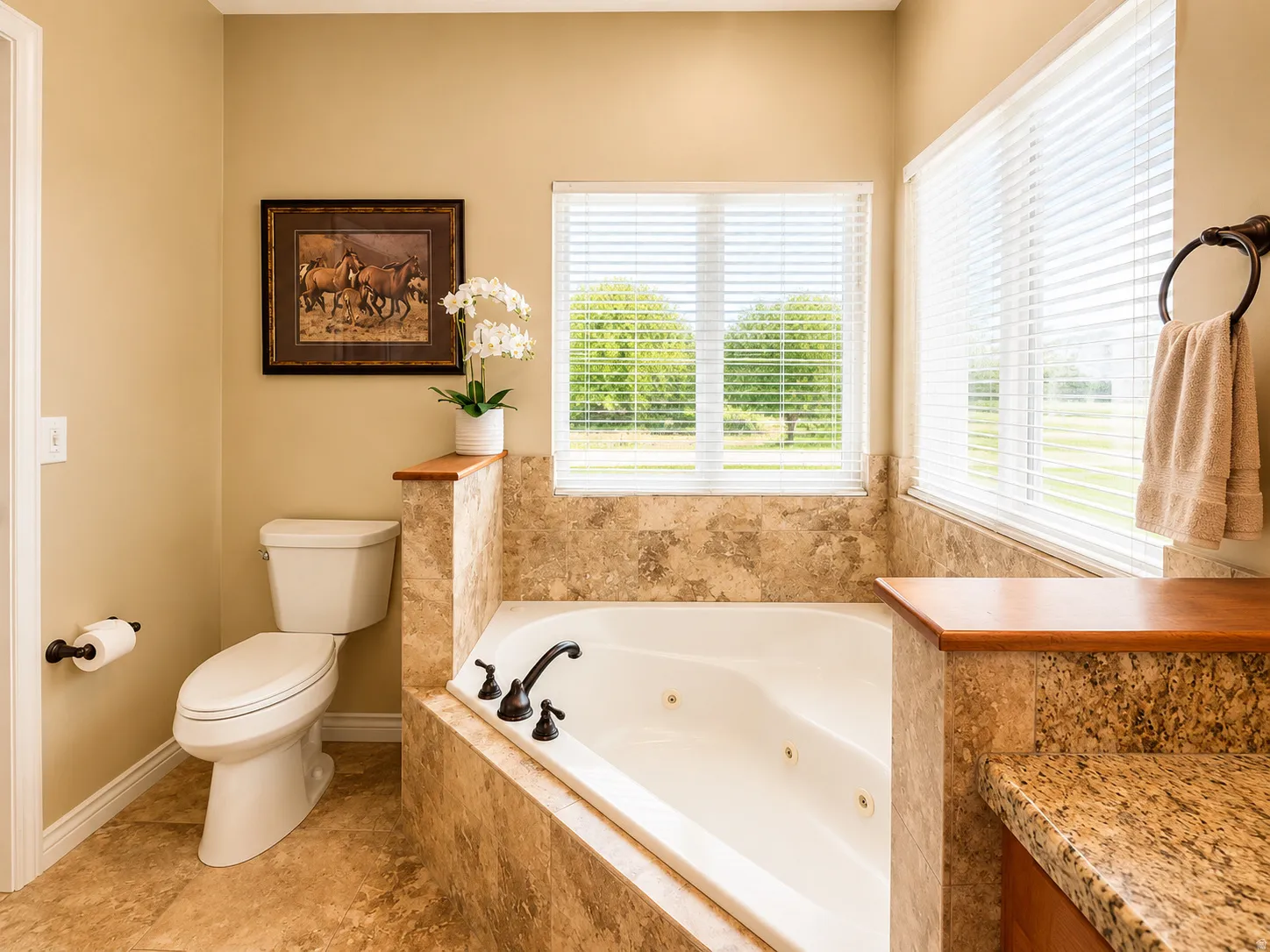 Soaking tub with bronze fixtures, surrounded by stone tile and wood-finish accents