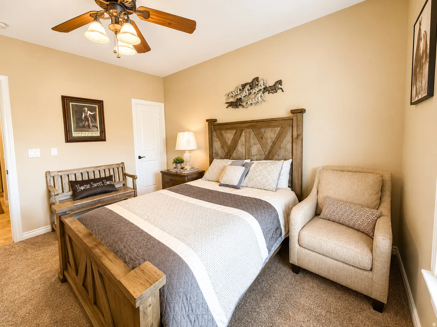 Carpeted bedroom featuring a wooden headboard, recessed closet door with black hardware, and a ceiling fan with light fixture