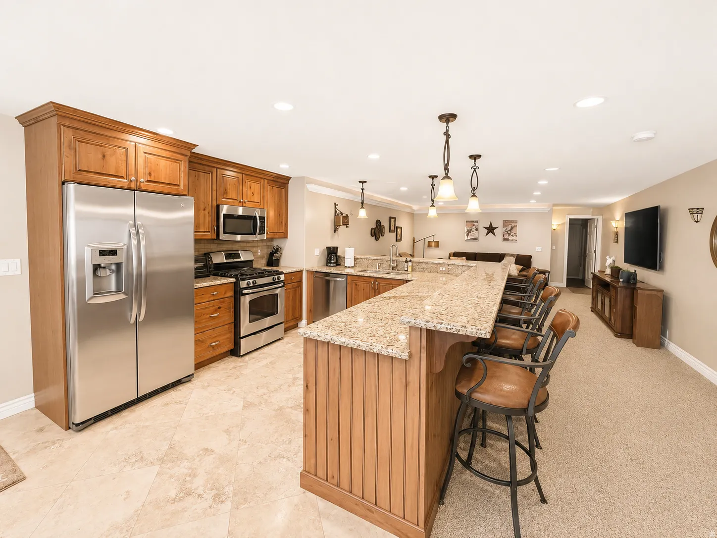 Full kitchen featuring stainless steel appliances, wood cabinetry, and a granite countertop island with pendant lighting