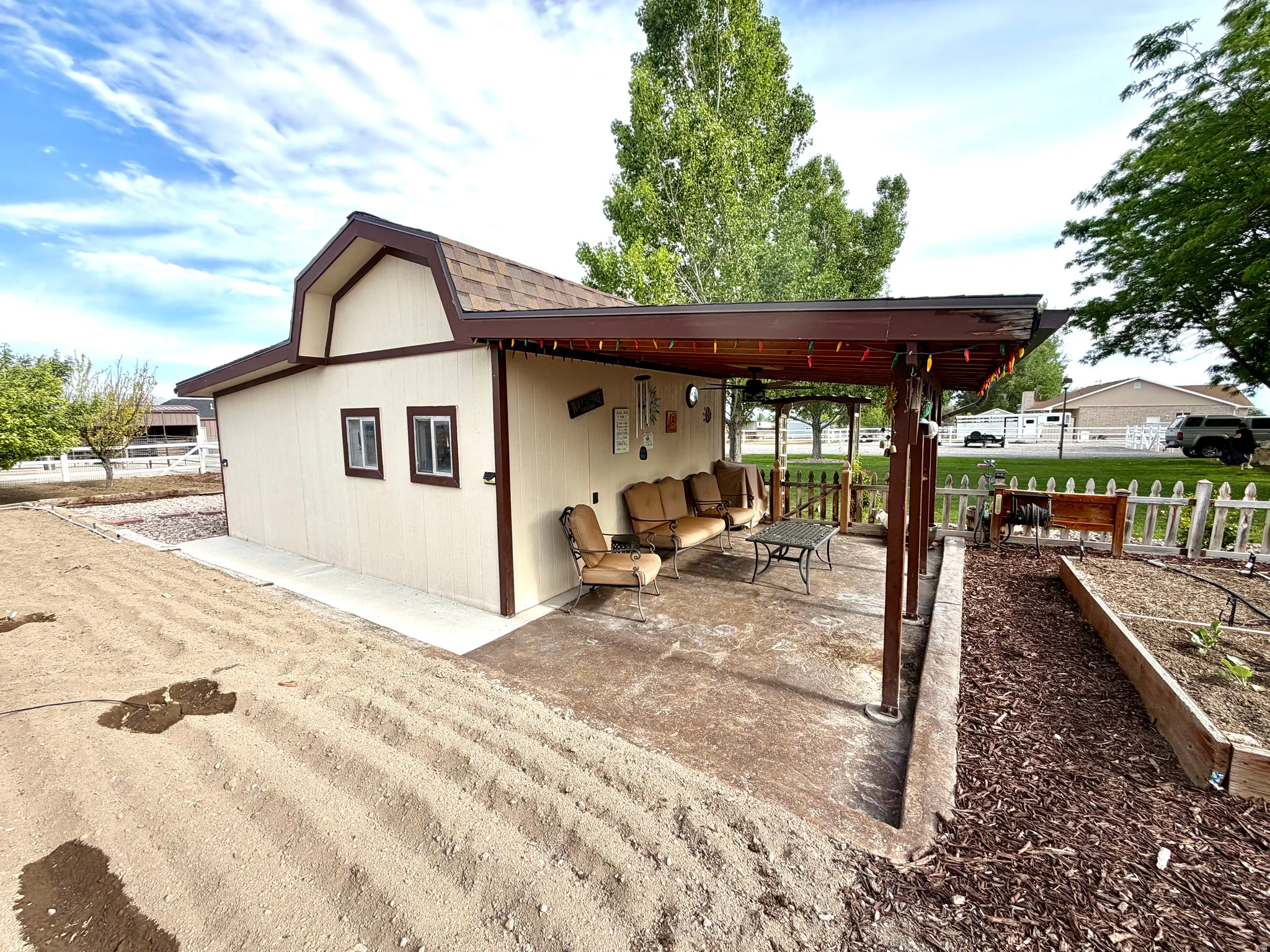Barn-style outbuilding featuring a covered patio, concrete flooring, and an adjacent raised garden bed