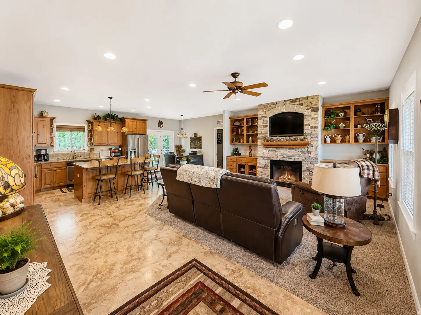 Open-concept living area featuring a stone-faced fireplace with hearth, a wood mantel, and built-in shelving