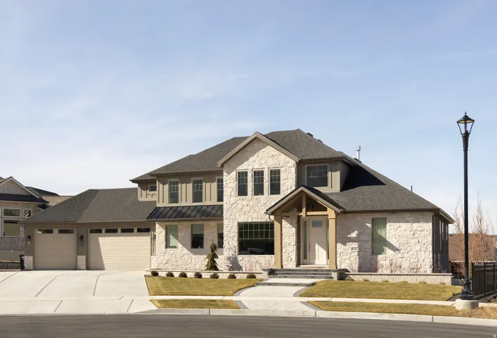 Stone veneer exterior with wood accents, a covered front entry, and a multi-car garage with overhead doors