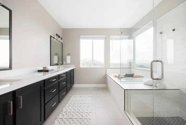Spacious bathroom featuring a dual vanity with white countertops, dark cabinetry, and integrated sinks