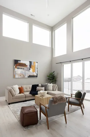Two-story living area featuring high ceilings, upper-level transom windows, wood-finish flooring, and sliding glass doors