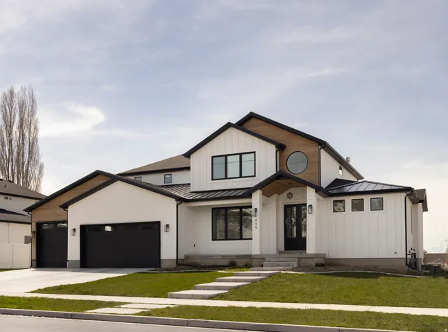 Modern farmhouse-inspired exterior featuring white board-and-batten siding, black-framed windows, and a prominent round window accent