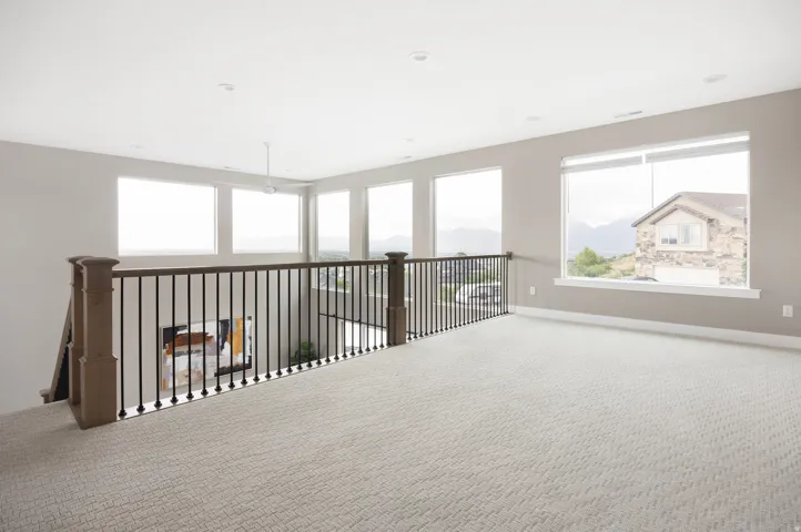 Spacious upper-level loft featuring light-toned carpeting and neutral wall paint