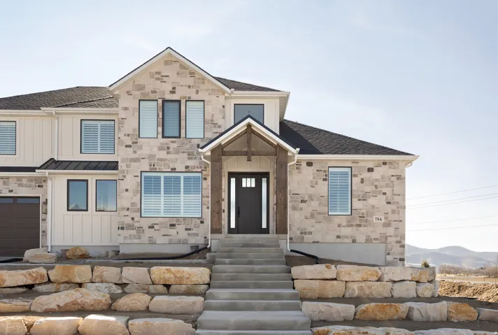 Stone and vertical plank siding exterior with a pitched roofline, prominent gabled entry, and dark-framed windows