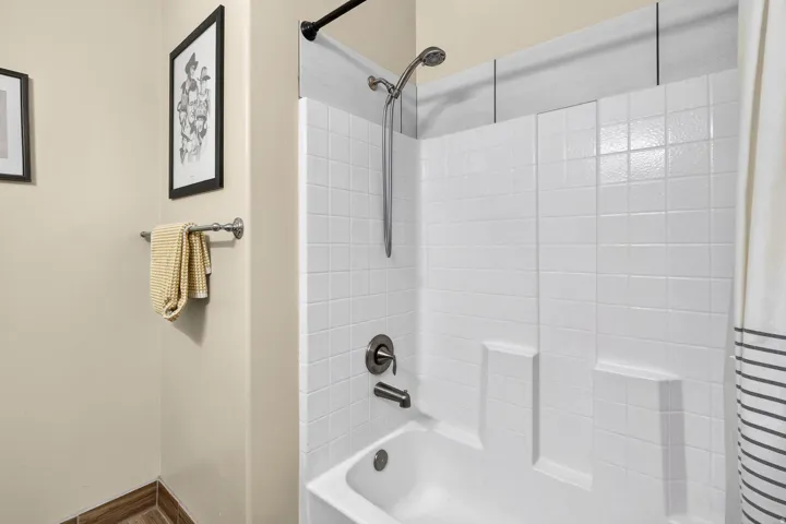 Built-in white tub and shower combination featuring a dark bronze shower fixture