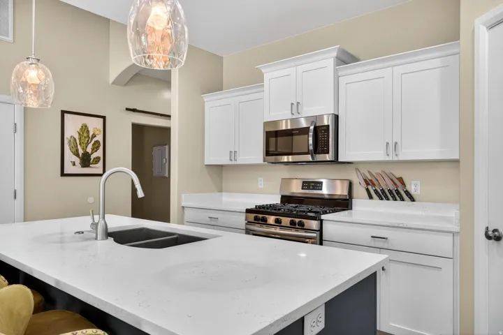 Modern kitchen featuring white cabinetry, stainless steel appliances, a gas range, and a dual-basin sink with a gooseneck faucet