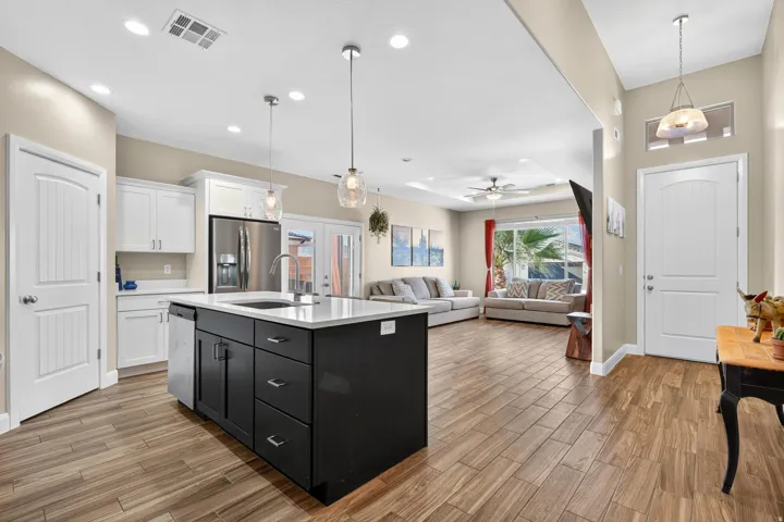 Open concept living area featuring wood-finish flooring, a kitchen island with a light-toned countertop, white cabinetry, and stainless steel appliances
