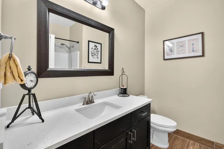 Bathroom featuring a dark wood-finish vanity with an integrated white sink, light-colored countertop, and brushed nickel faucet