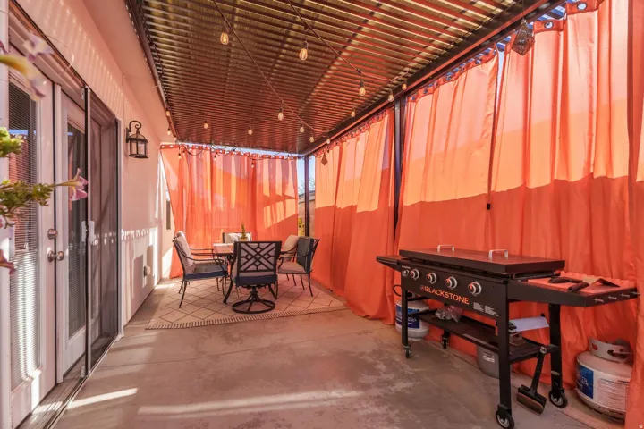 Covered patio featuring a corrugated metal roof, string lighting, and an exterior wall lantern