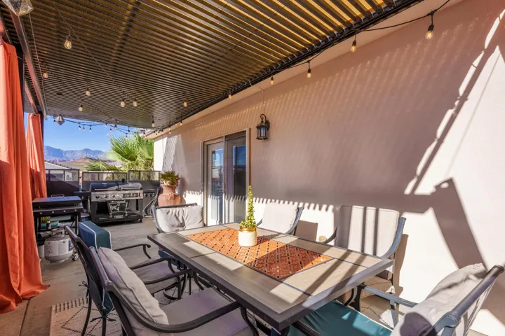 Covered patio featuring a corrugated metal ceiling with string lighting, a wall-mounted outdoor lantern, and a sliding glass door for interior access