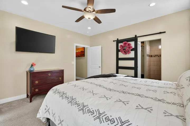 Recessed lighting illuminates this space, featuring a ceiling fan and an integrated wall-mounted television
