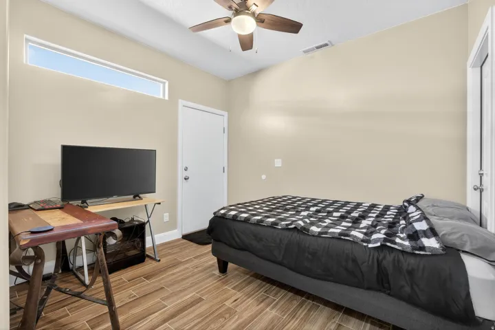 Room featuring wood-finish flooring, a contemporary ceiling fan, a clerestory window, and neutral wall tones