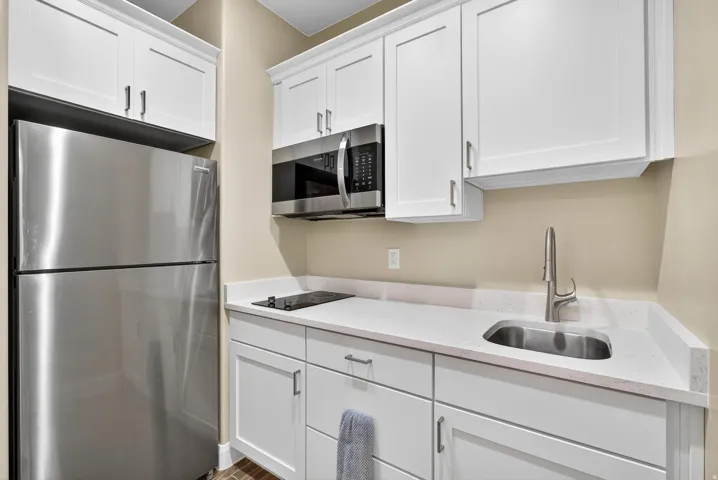 Compact kitchen featuring white shaker cabinetry and light-toned countertops