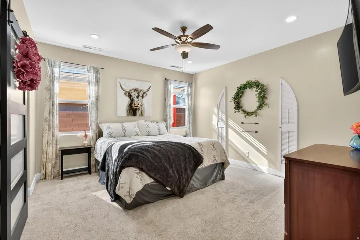 Carpeted bedroom featuring a ceiling fan with integrated lighting, recessed lighting, and two windows