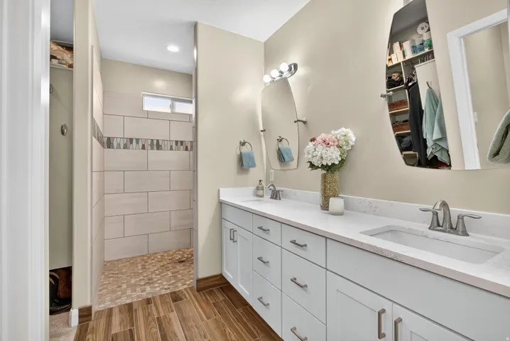 Dual vanity with undermount sinks and light-colored countertops, set against wood-finish flooring