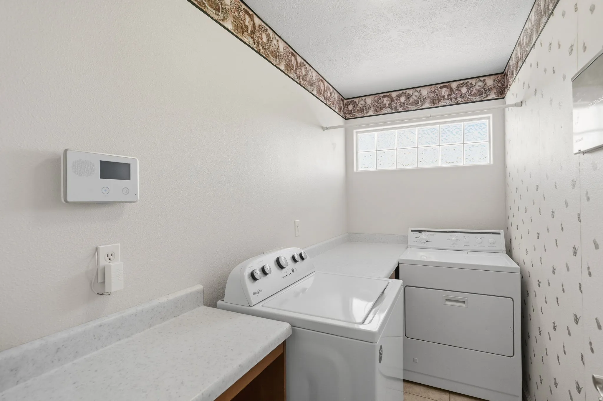 Dedicated laundry space featuring a top-load washer, front-load dryer, and a built-in countertop with storage